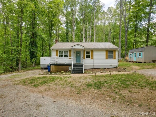 view of front of home featuring a storage shed, a porch, crawl space, a chimney, and an outdoor structure