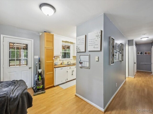 kitchen featuring white dishwasher, baseboards, plenty of natural light, and light wood finished floors