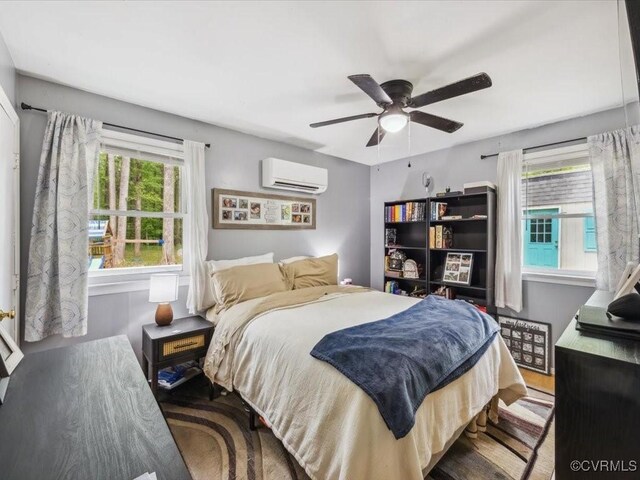 bedroom featuring ceiling fan, an AC wall unit, and wood finished floors
