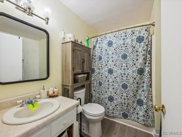 bathroom with vanity, a shower with curtain, toilet, and wood finished floors
