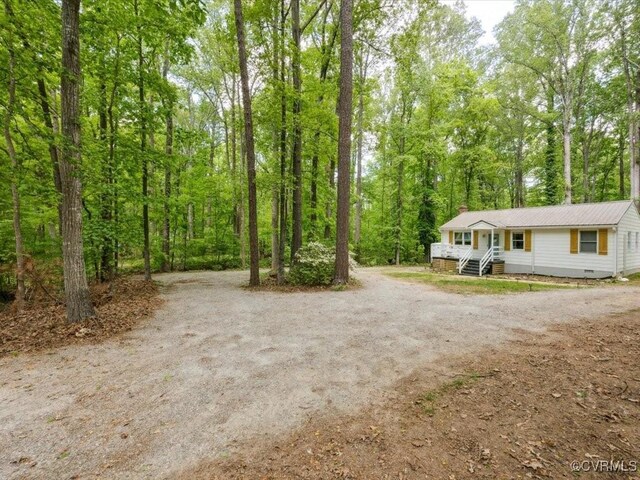 view of yard with a forest view and driveway