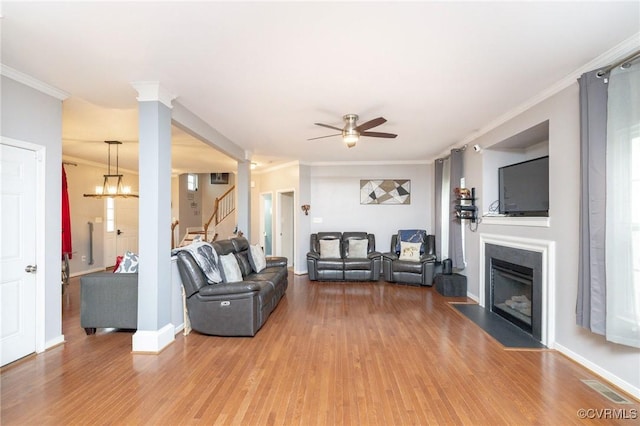 living area with ornamental molding, light wood finished floors, a ceiling fan, and stairs