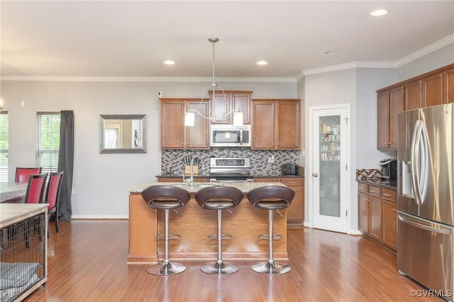kitchen with a breakfast bar, dark wood-style flooring, brown cabinets, and stainless steel appliances