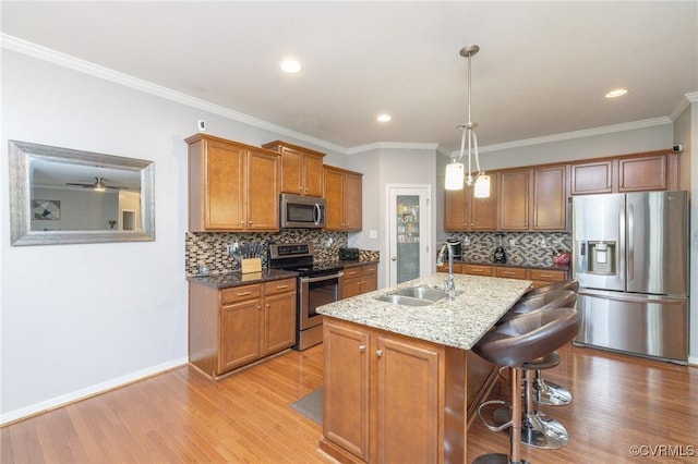 kitchen featuring brown cabinets, appliances with stainless steel finishes, light wood-style flooring, and a sink