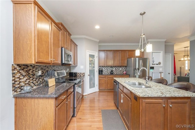 kitchen featuring appliances with stainless steel finishes, light wood-style floors, brown cabinets, and a sink