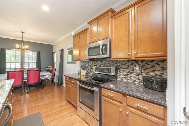 kitchen with tasteful backsplash, brown cabinets, light wood-style flooring, stainless steel appliances, and an inviting chandelier
