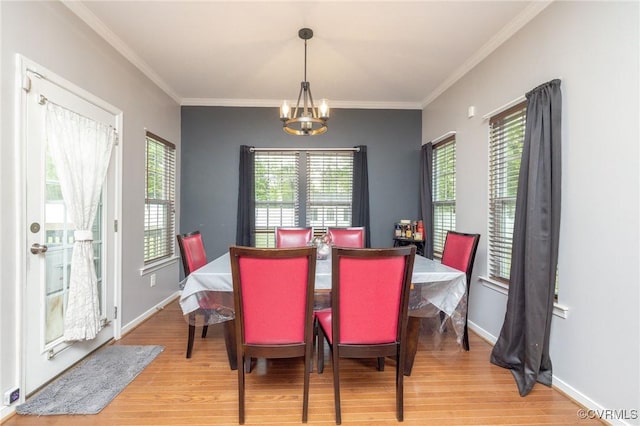 dining space featuring ornamental molding, an inviting chandelier, wood finished floors, and baseboards