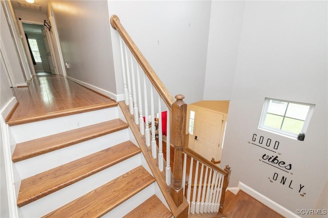 staircase with wood finished floors, visible vents, and baseboards