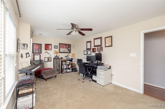 office featuring light colored carpet, ceiling fan, and baseboards