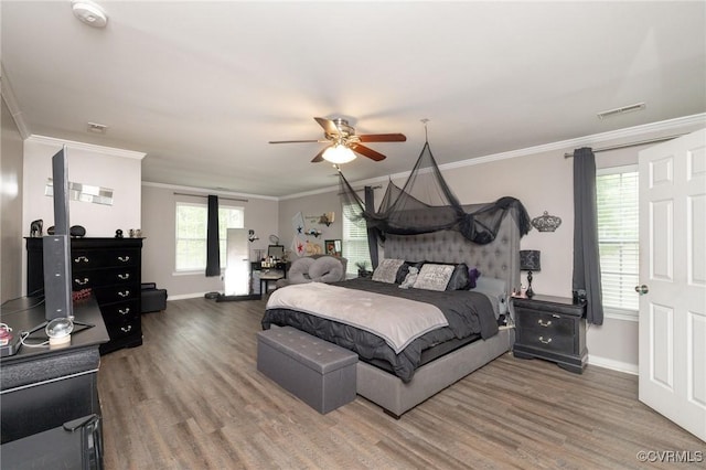 bedroom featuring visible vents, wood finished floors, ornamental molding, and baseboards