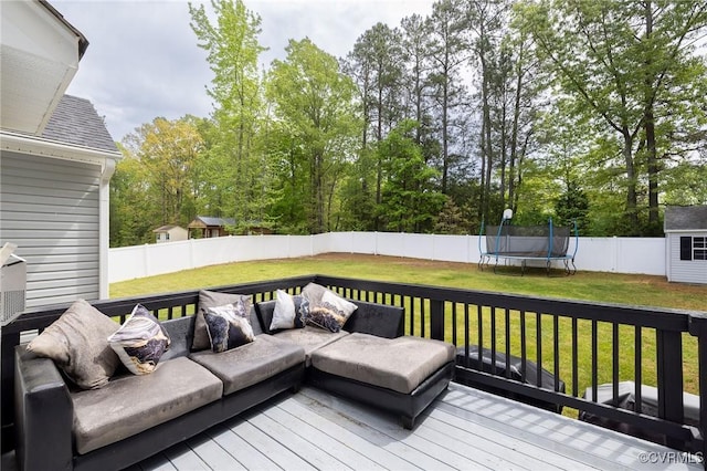 wooden deck with a fenced backyard, a yard, outdoor lounge area, and a trampoline