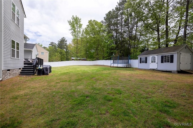 view of yard featuring a trampoline, an outbuilding, a fenced backyard, a shed, and a deck