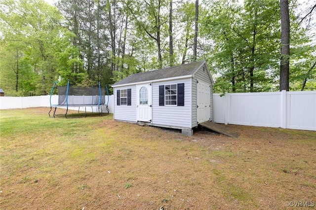 view of outbuilding with an outbuilding, a trampoline, and a fenced backyard
