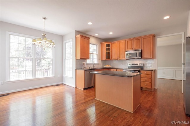 kitchen with a notable chandelier, a sink, dark countertops, appliances with stainless steel finishes, and dark wood-style floors