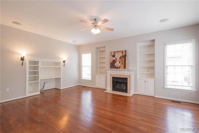unfurnished living room featuring ceiling fan, baseboards, a fireplace with flush hearth, and wood finished floors