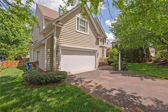 view of side of property with a yard, aphalt driveway, an attached garage, and fence