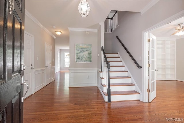entryway with stairs, crown molding, and wood finished floors