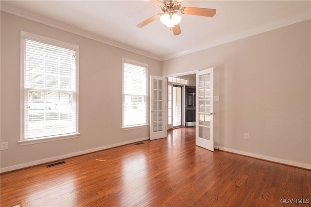 spare room featuring french doors, wood finished floors, crown molding, ceiling fan, and baseboards