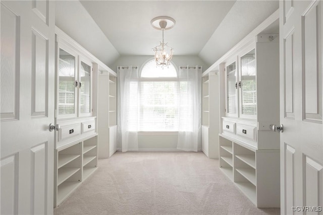 spacious closet featuring vaulted ceiling, a chandelier, and carpet flooring