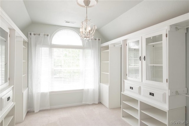 walk in closet featuring vaulted ceiling, a chandelier, light colored carpet, and visible vents