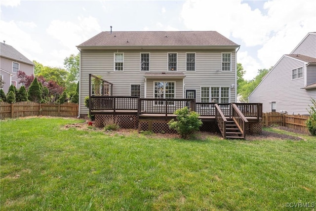 rear view of property featuring a lawn, a wooden deck, and a fenced backyard
