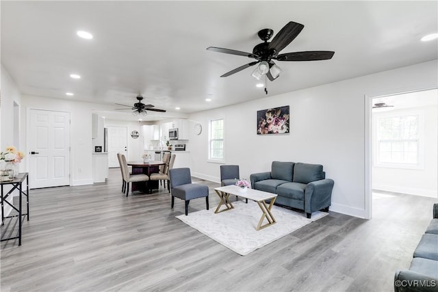 living room featuring a ceiling fan, baseboards, recessed lighting, and light wood finished floors