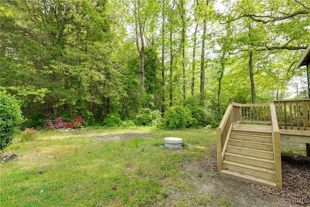view of yard with stairs, a view of trees, and a deck