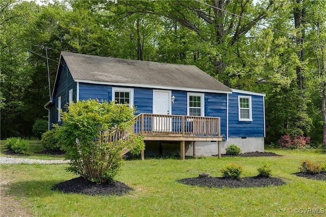 view of front of home with a wooden deck, a shingled roof, and a front yard
