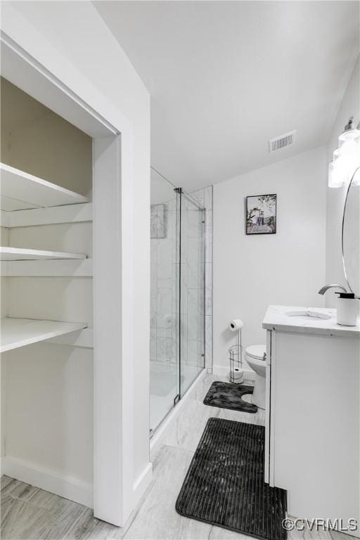 bathroom with vanity, visible vents, toilet, baseboards, and a stall shower