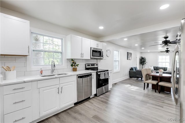 kitchen with white cabinets, a sink, stainless steel appliances, baseboards, and recessed lighting