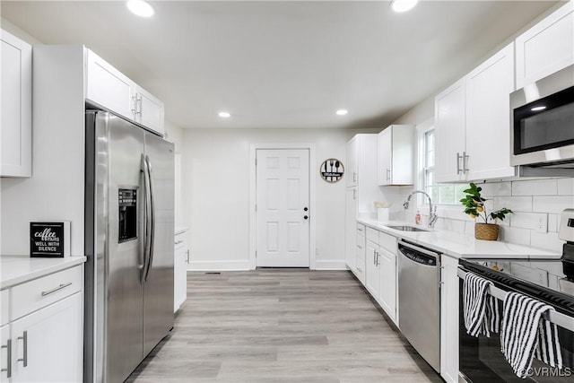 kitchen featuring recessed lighting, a sink, white cabinets, and stainless steel appliances