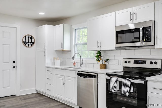 kitchen with a sink, light wood finished floors, white cabinets, and stainless steel appliances