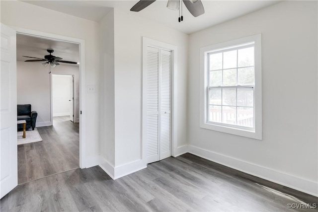 unfurnished bedroom featuring dark wood-type flooring, baseboards, ceiling fan, and a closet