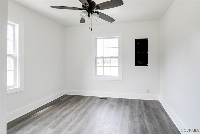 spare room with baseboards, ceiling fan, wood finished floors, and visible vents