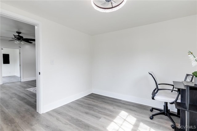 unfurnished office with a ceiling fan, baseboards, and wood finished floors