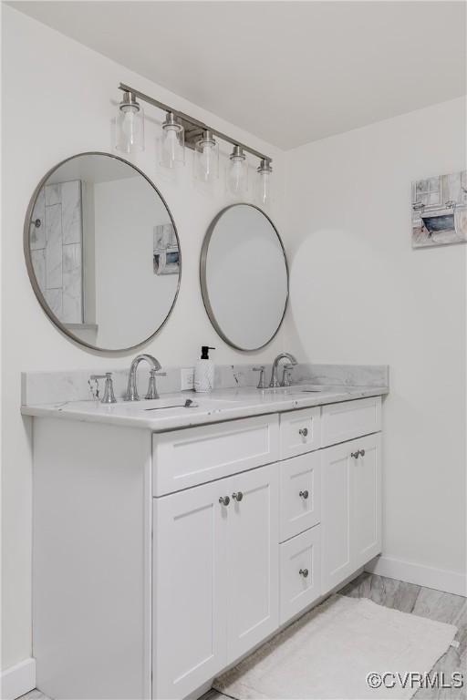 full bathroom featuring a sink, baseboards, and double vanity