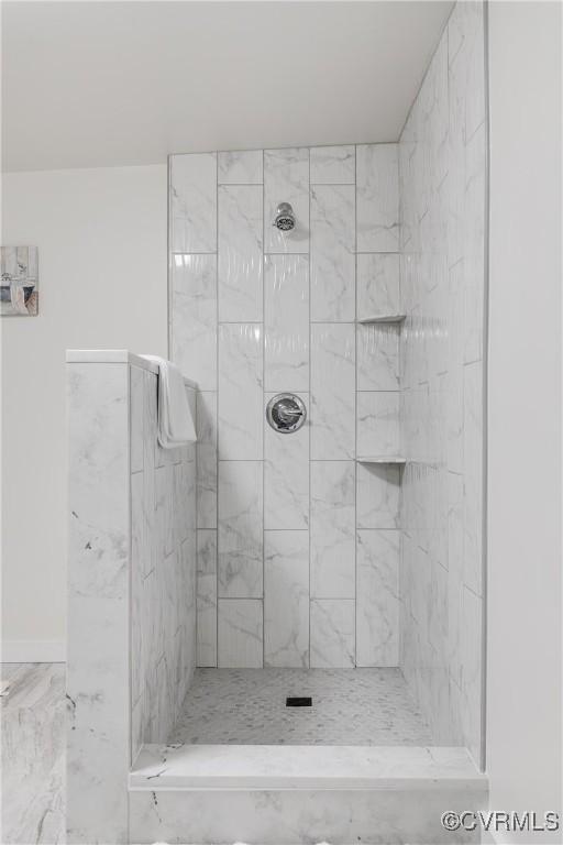 full bath with tiled shower and marble finish floor