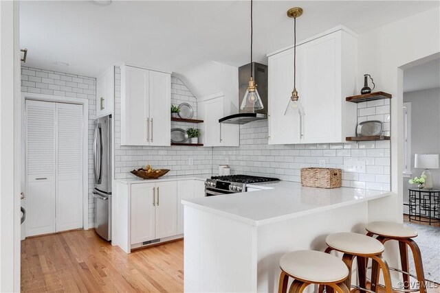 kitchen featuring wall chimney exhaust hood, a peninsula, open shelves, and stainless steel appliances