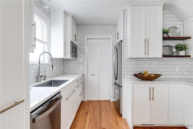 kitchen with tasteful backsplash, stainless steel appliances, light countertops, and a sink