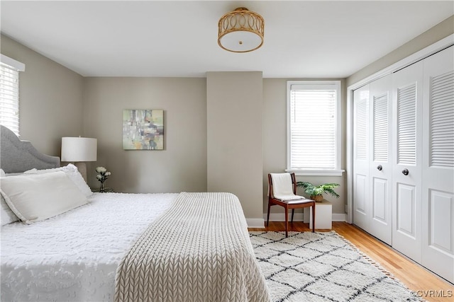 bedroom featuring baseboards, light wood finished floors, and a closet