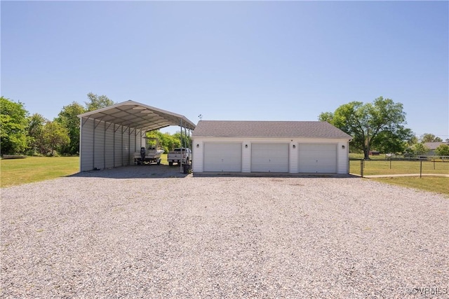 detached garage featuring fence, a carport, and driveway