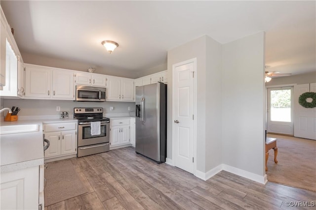 kitchen featuring white cabinetry, a sink, stainless steel appliances, light countertops, and light wood finished floors
