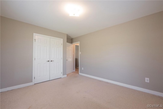 unfurnished bedroom featuring a closet, light carpet, and baseboards
