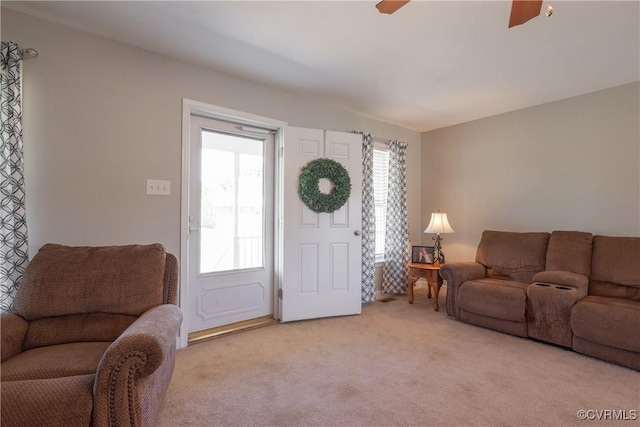 living room with a ceiling fan, light carpet, and plenty of natural light