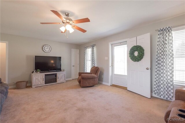 living area with a wealth of natural light, a ceiling fan, and carpet