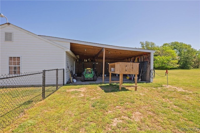 view of yard with fence, an outdoor structure, a pole building, and an attached carport