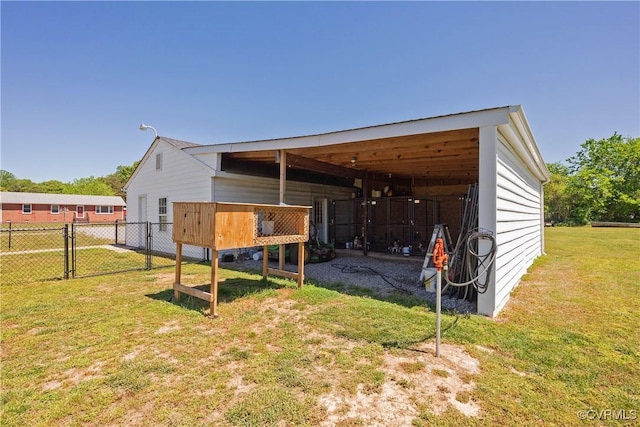 view of pole building featuring a lawn, a carport, a gate, and fence