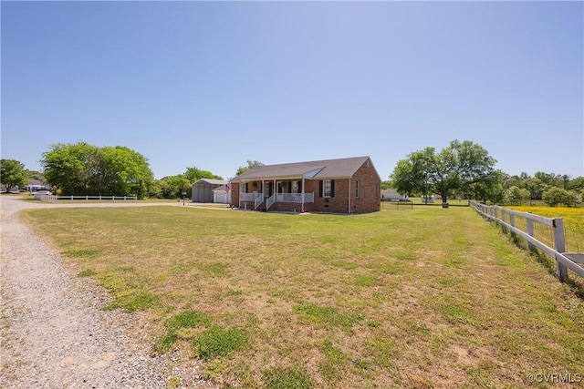 exterior space featuring an outdoor structure, a shed, covered porch, a front yard, and fence