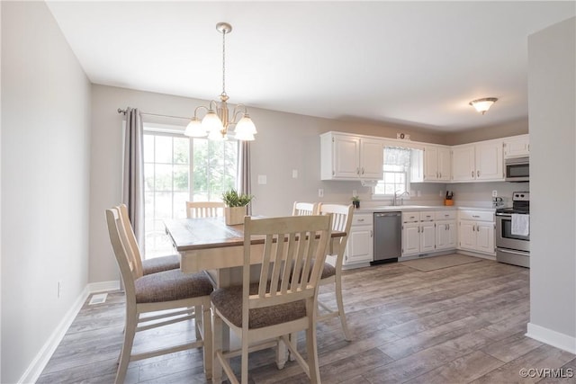 dining area featuring baseboards, a notable chandelier, and light wood-style floors