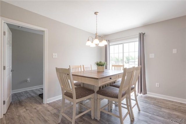 dining room with wood finished floors, a chandelier, and baseboards